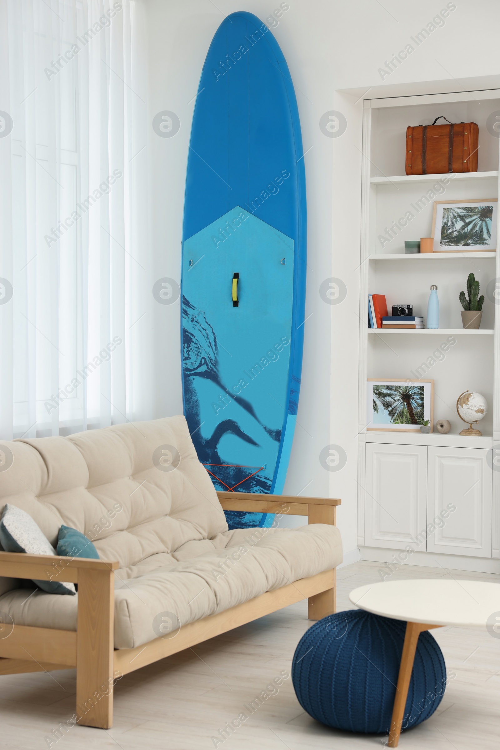 Photo of SUP board and modern furniture in stylish living room. Interior design