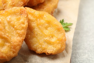 Photo of Tasty fried chicken nuggets on light grey table, closeup