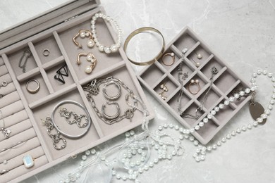 Photo of Jewelry boxes with many different accessories on light grey table, flat lay