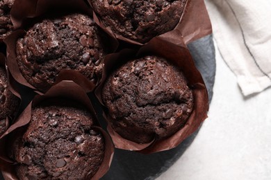 Tasty chocolate muffins on light table, top view