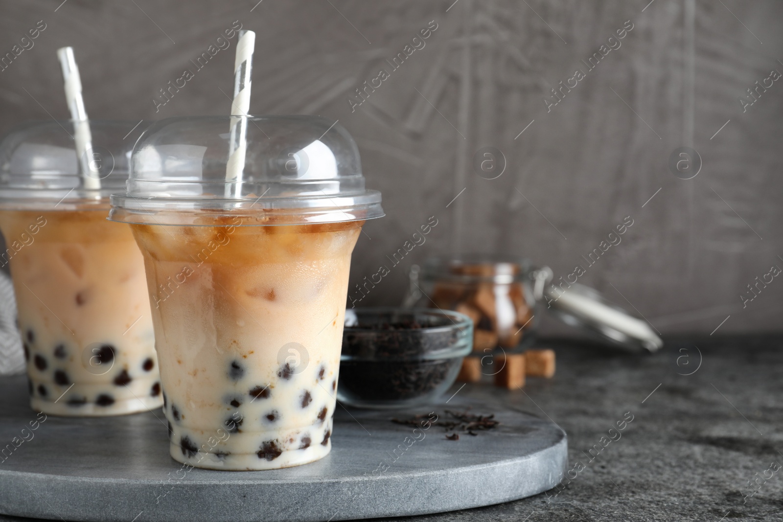 Photo of Tasty milk bubble tea on grey table, closeup. Space for text