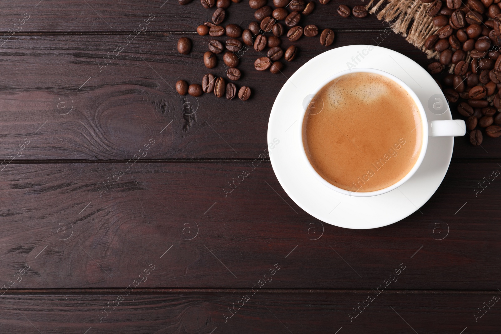 Photo of Cup of hot aromatic coffee and roasted beans on wooden table, flat lay. Space for text