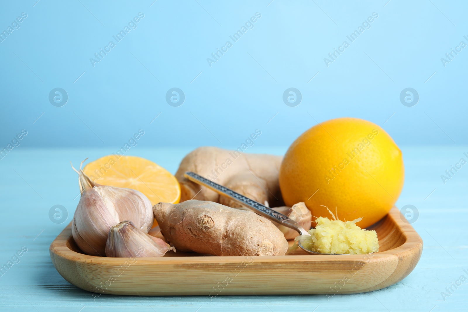 Photo of Fresh garlic and other natural cold remedies on light blue wooden table