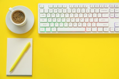 Photo of Modern keyboard with RGB lighting and stationery on yellow background, flat lay. Space for text