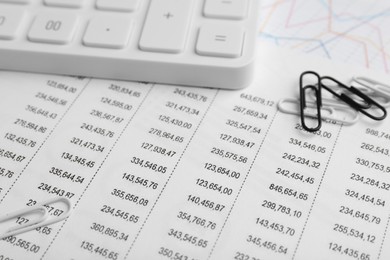 Paper clips and calculator on accounting documents with data, closeup