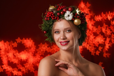 Photo of Beautiful young woman wearing Christmas wreath on blurred background. Bokeh effect