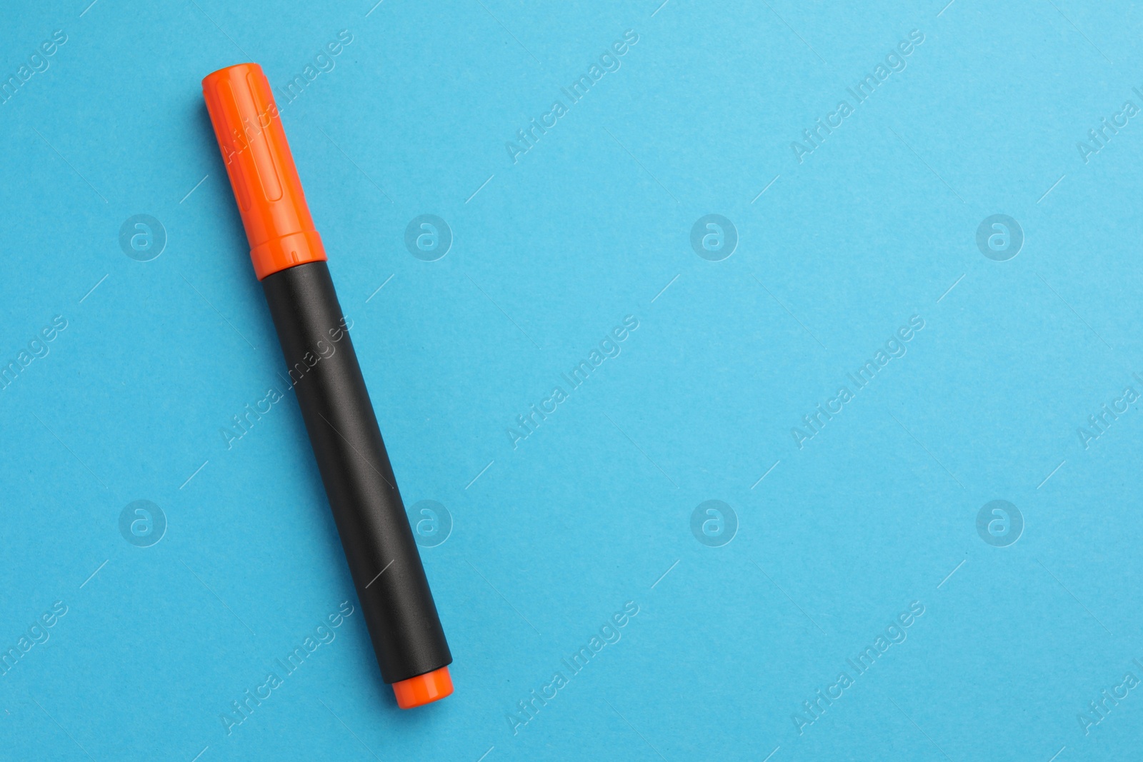 Photo of Bright orange marker on light blue background, top view. Space for text