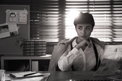 Photo of Old fashioned detective with newspaper at table in office. Black and white effect