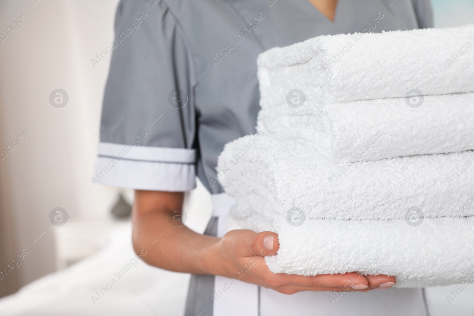 Photo of Chambermaid with stack of fresh towels in hotel room, closeup. Space for text