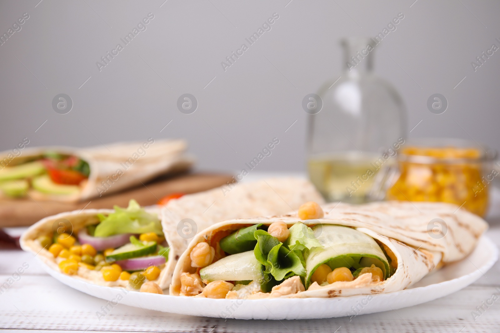 Photo of Delicious hummus wraps with vegetables on table, closeup. Space for text