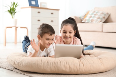 Little children using video chat on tablet at home