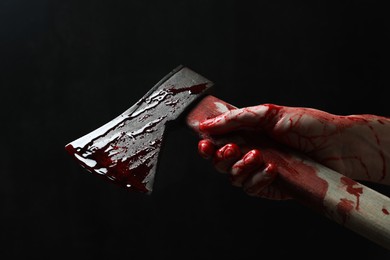 Photo of Man holding bloody axe on black background, closeup