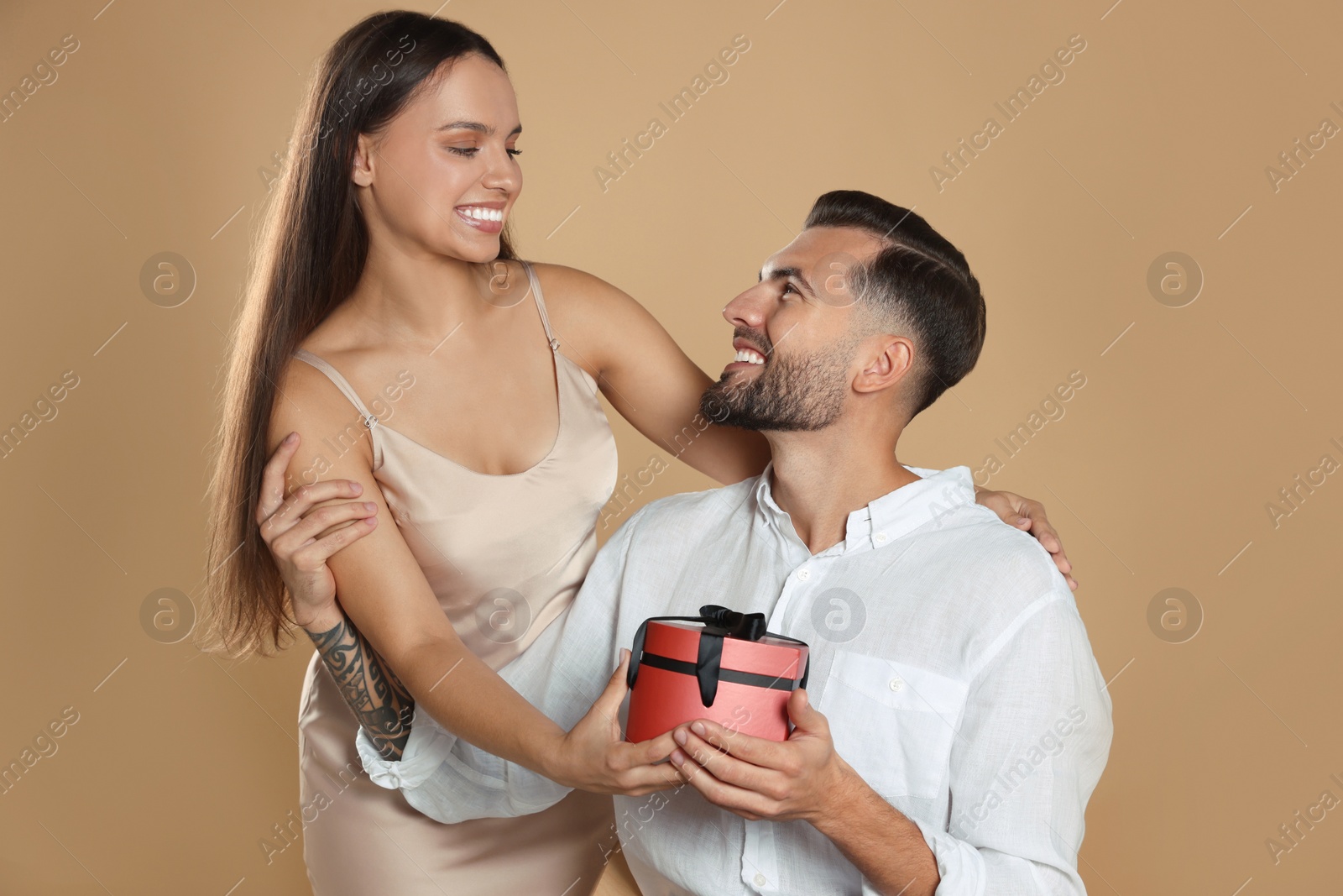 Photo of Lovely couple with gift on beige background