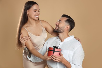 Photo of Lovely couple with gift on beige background