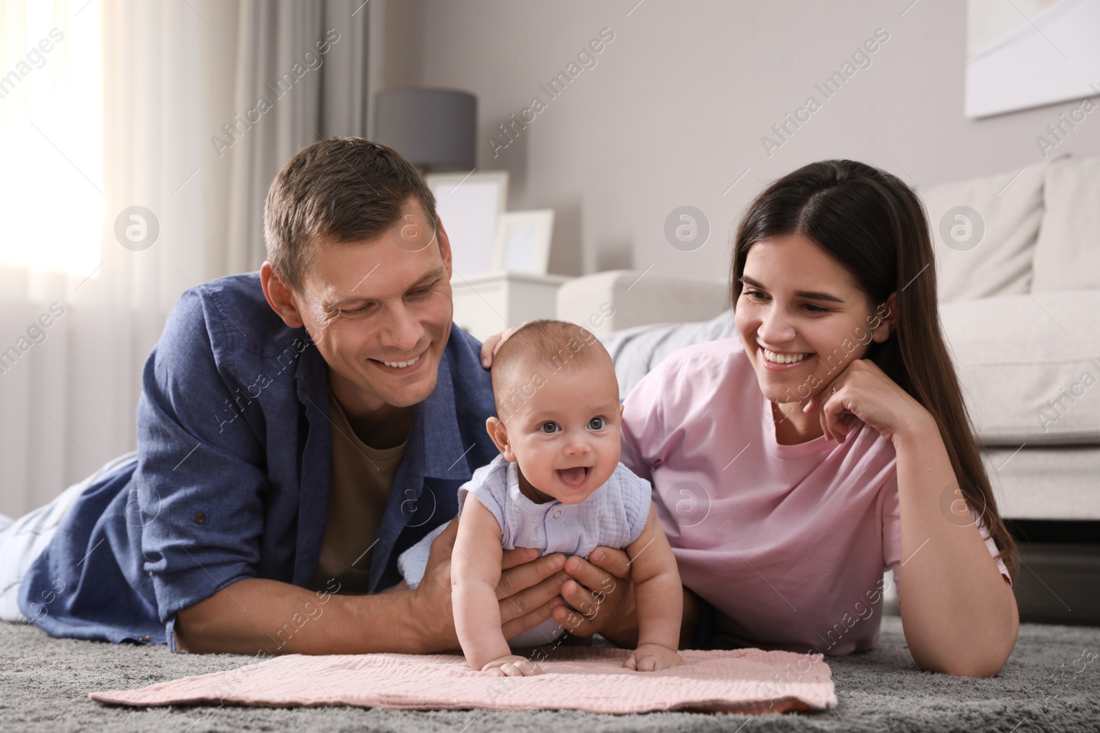 Photo of Happy family with their cute baby on floor at home