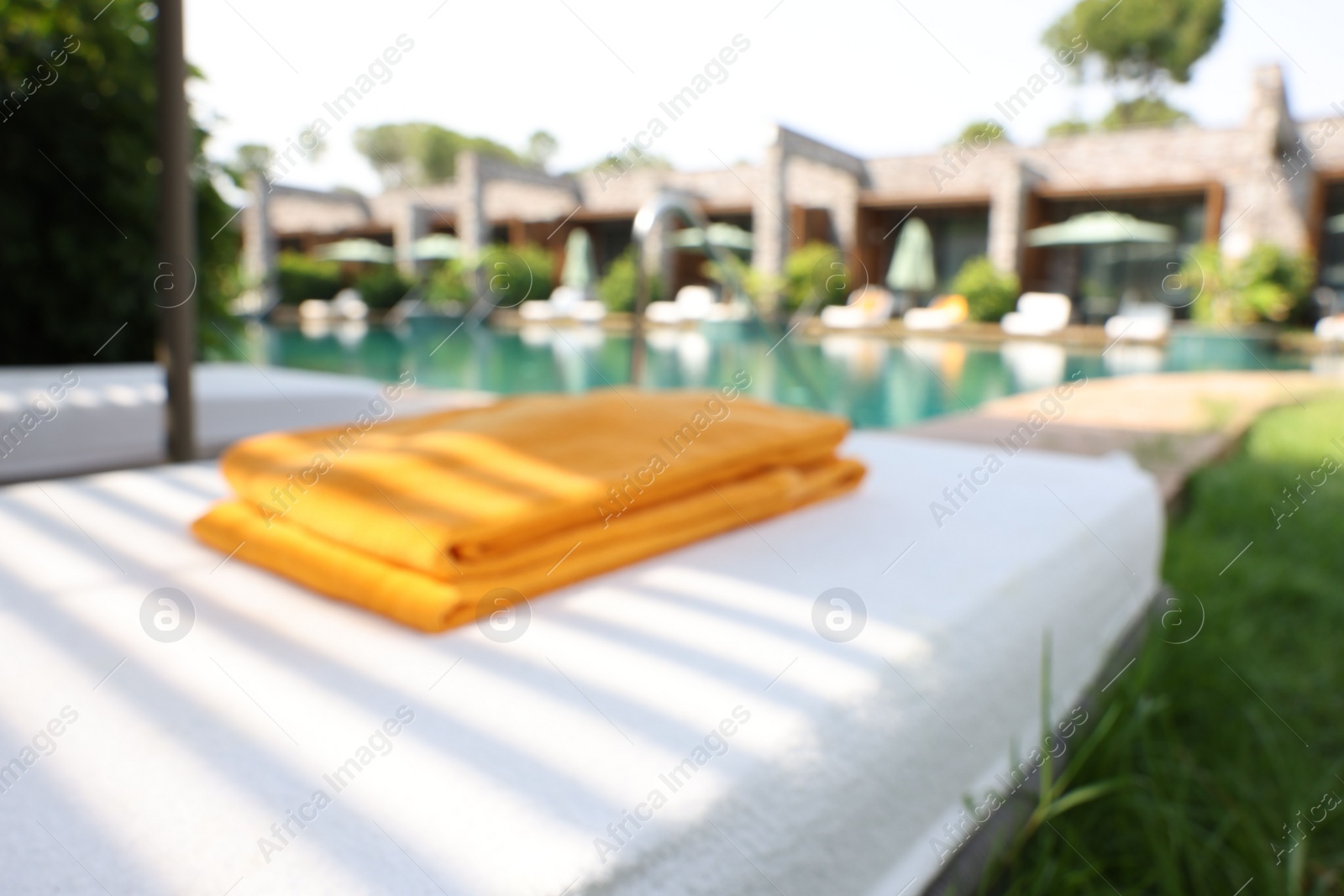 Photo of Sunbed near swimming pool at luxury resort, blurred view