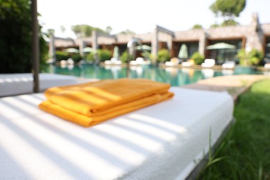 Sunbed near swimming pool at luxury resort, blurred view