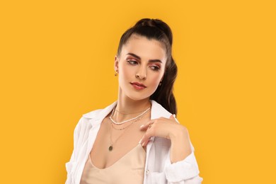 Beautiful woman with elegant jewelry on orange background