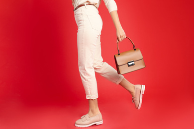 Photo of Young woman with stylish bag on red background, closeup