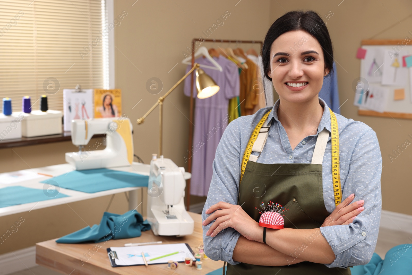 Photo of Professional dressmaker with measuring tape and pin cushion in workshop