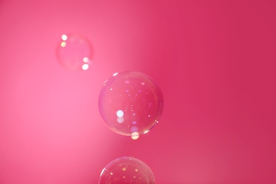 Photo of Beautiful translucent soap bubbles on pink background