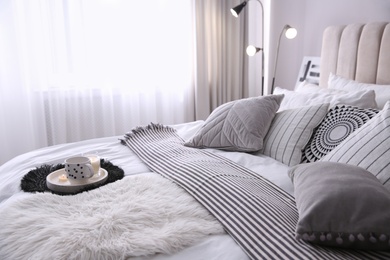 Photo of Bed with cushions and striped blanket in room. Interior design
