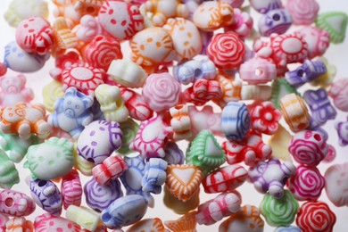 Photo of Pile of cute colorful ceramic beads on white background, closeup