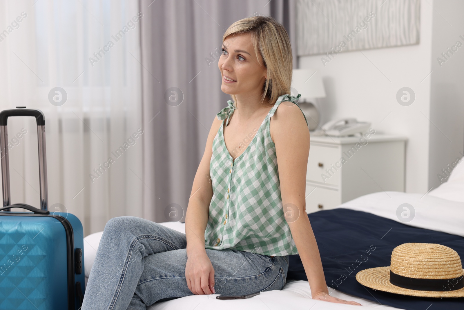 Photo of Smiling guest relaxing on bed in stylish hotel room