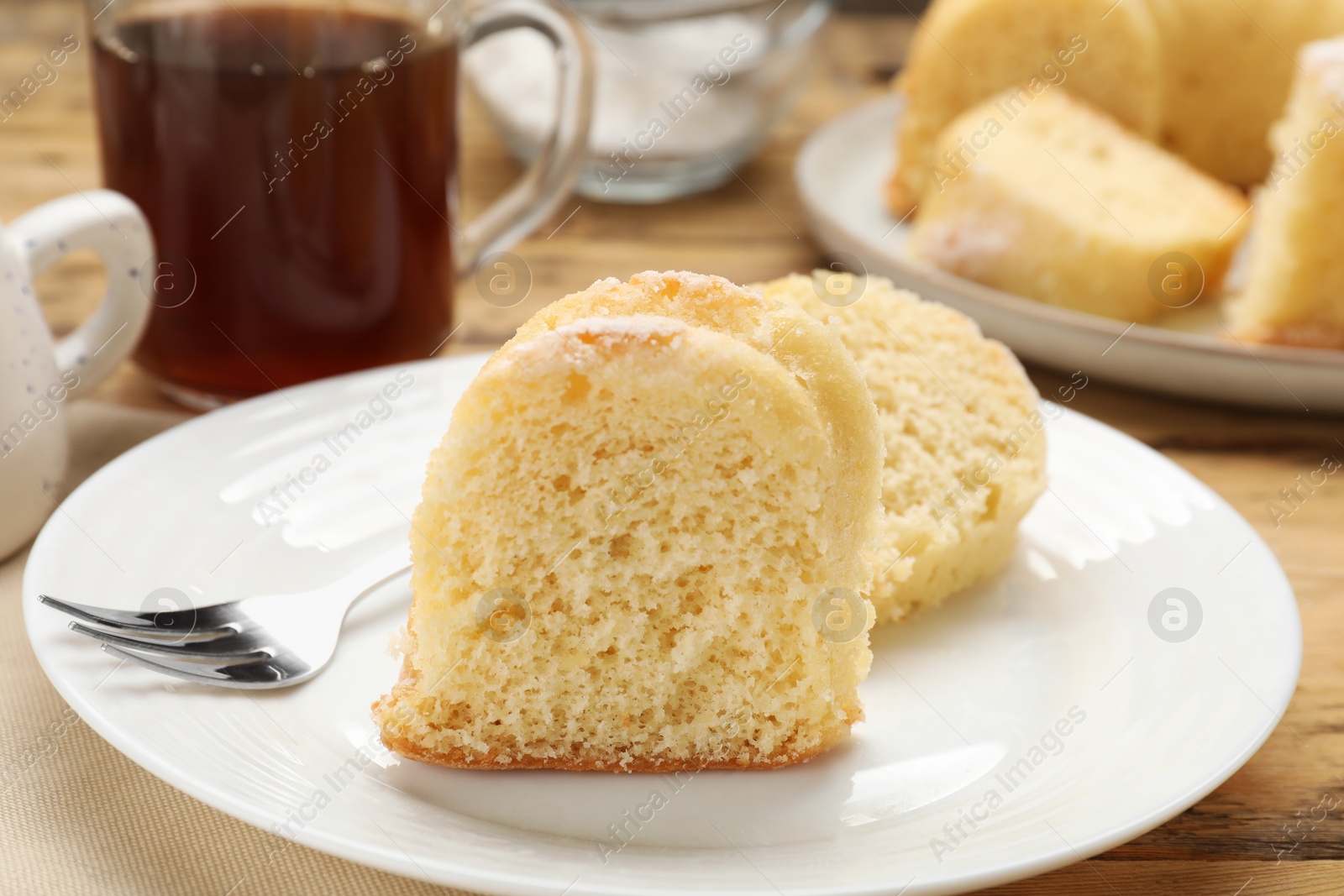 Photo of Pieces of delicious sponge cake and fork on wooden table, closeup