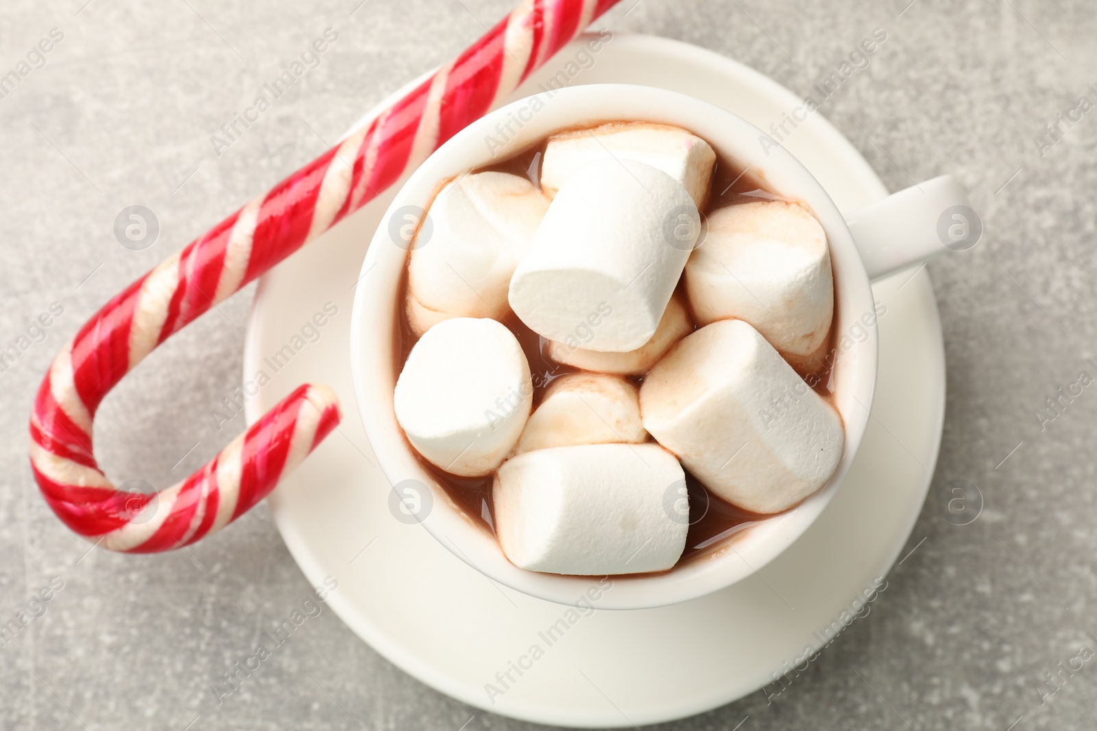 Photo of Tasty hot chocolate with marshmallows and candy cane on light grey table, top view