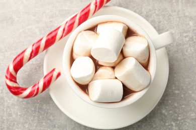 Photo of Tasty hot chocolate with marshmallows and candy cane on light grey table, top view