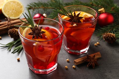 Photo of Delicious punch drink with cranberries, orange and spices on grey table