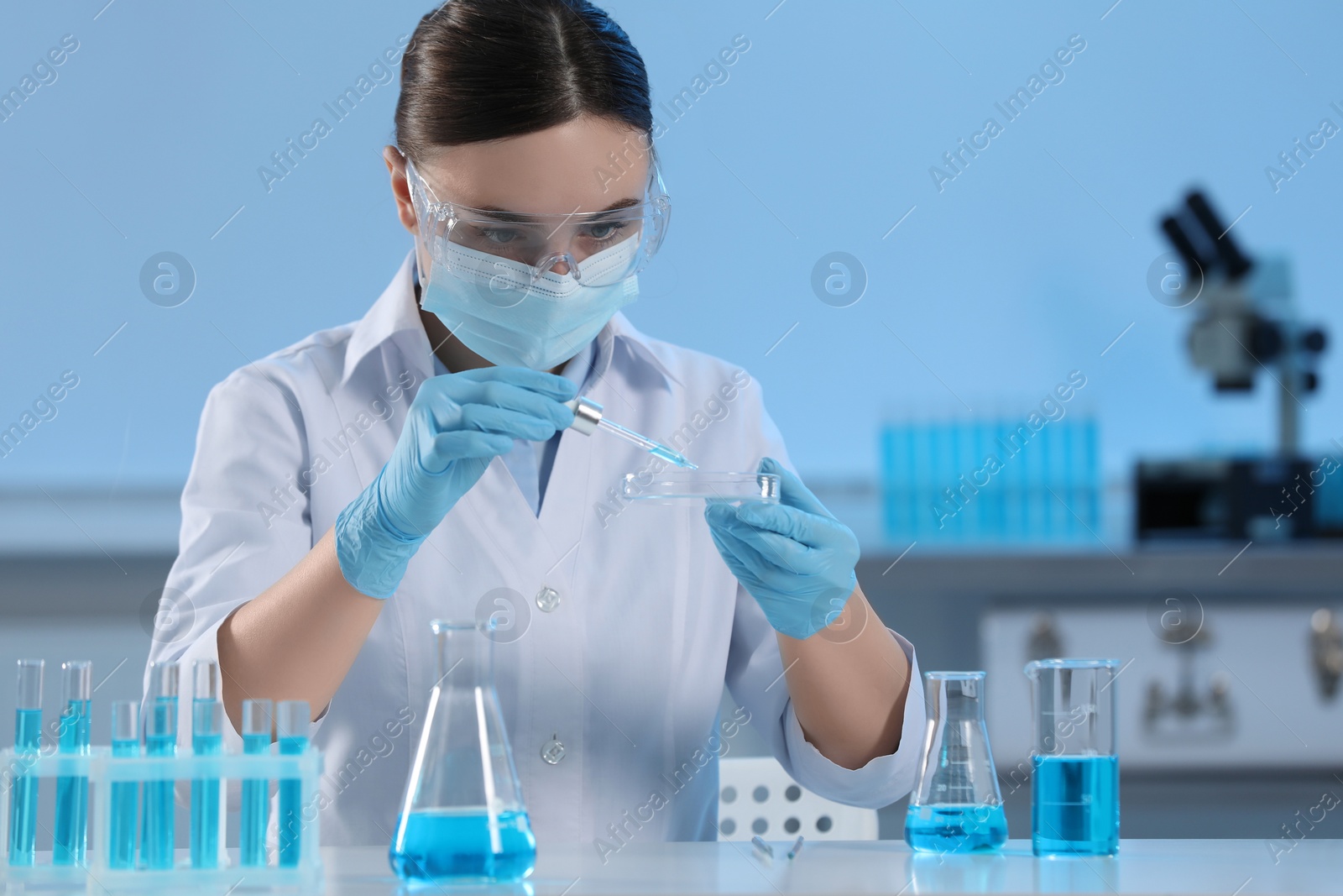 Photo of Scientist dripping liquid from pipette into petri dish in laboratory