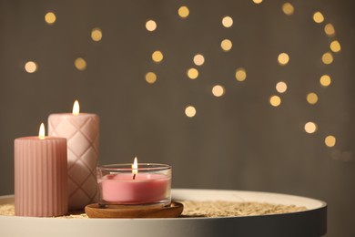 Photo of Burning candles on table against beige background. Space for text