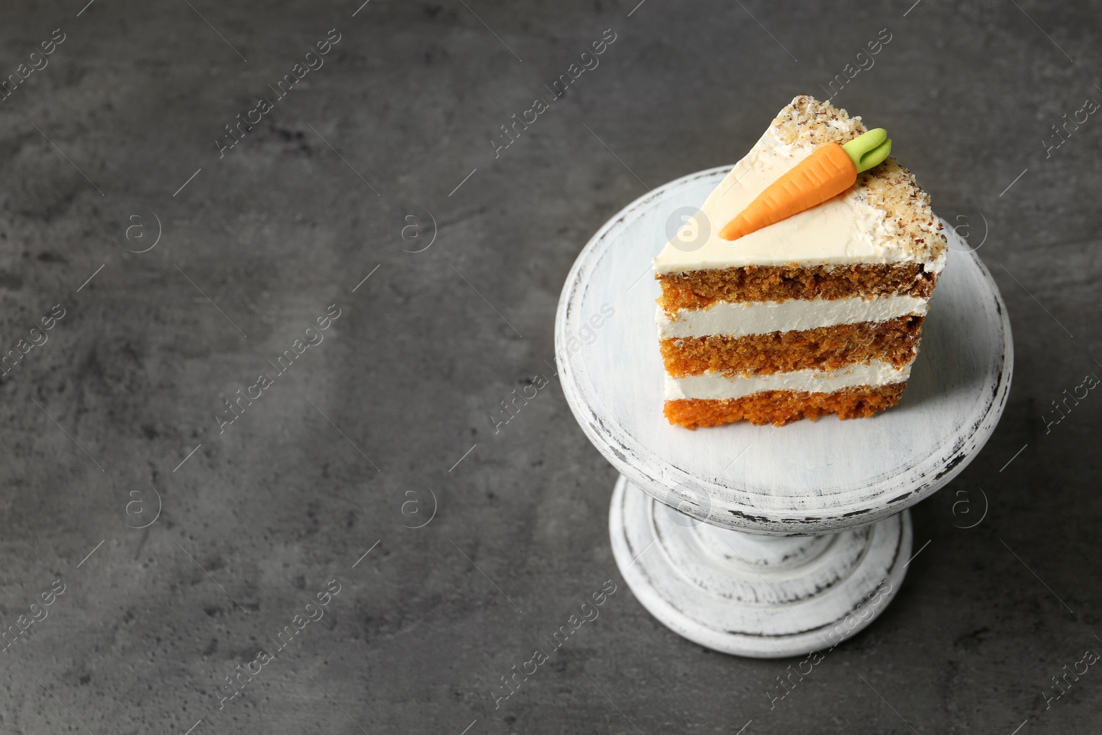 Photo of Stand with piece of carrot cake on grey table, above view. Space for text