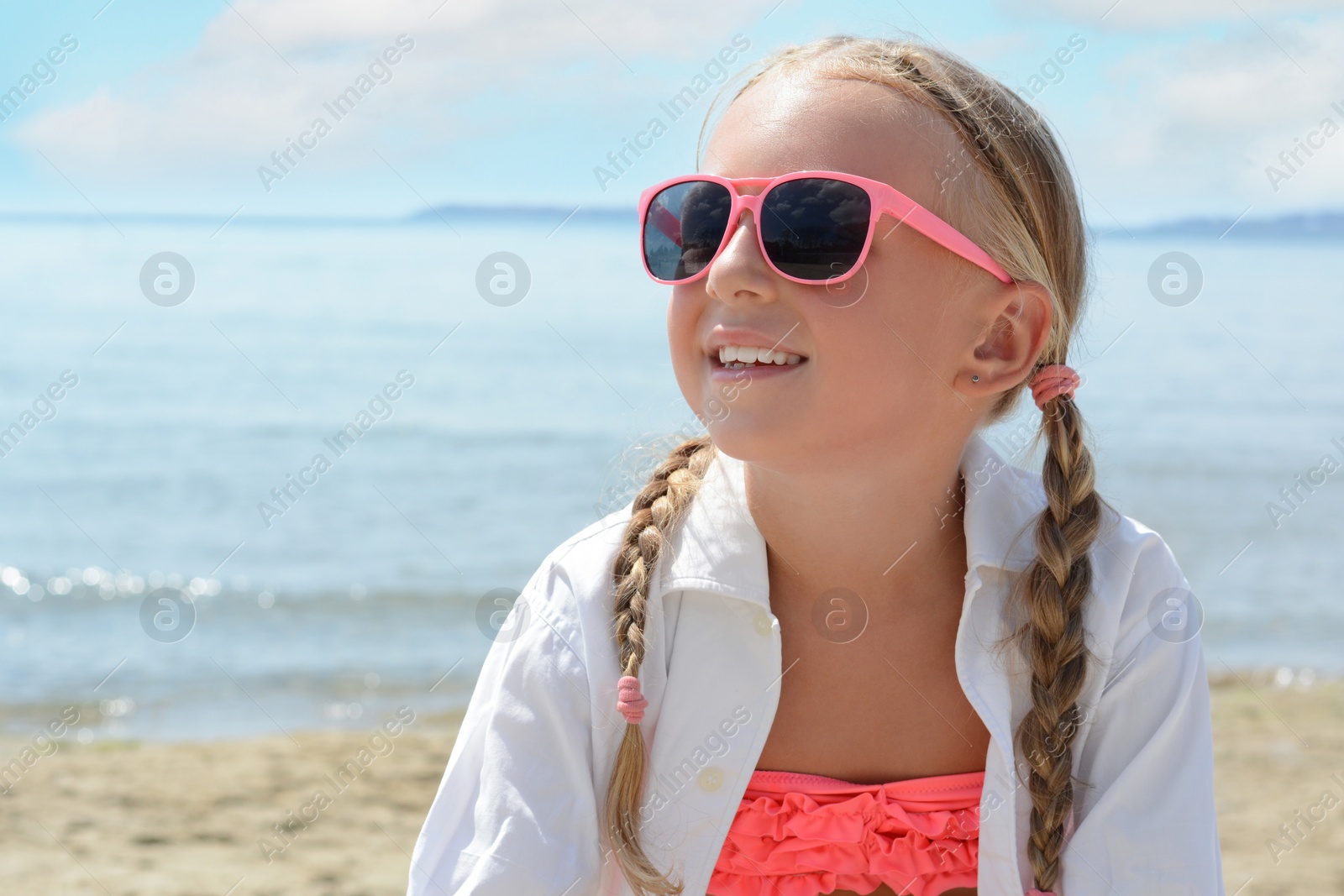 Photo of Little girl wearing sunglasses at beach on sunny day. Space for text