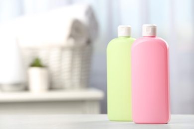 Bottles with hair care cosmetics on table in bathroom, space for text