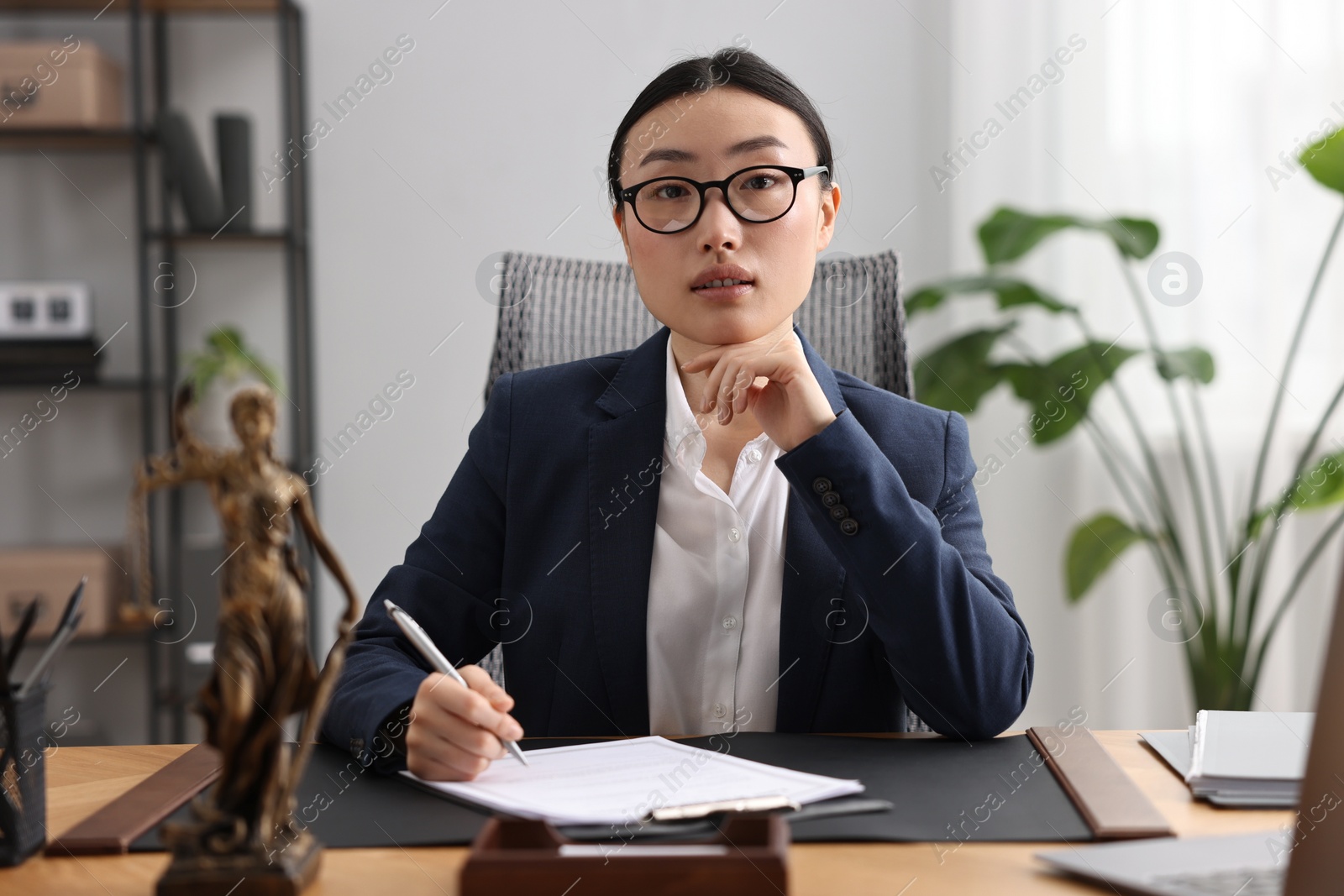 Photo of Notary signing document at table in office