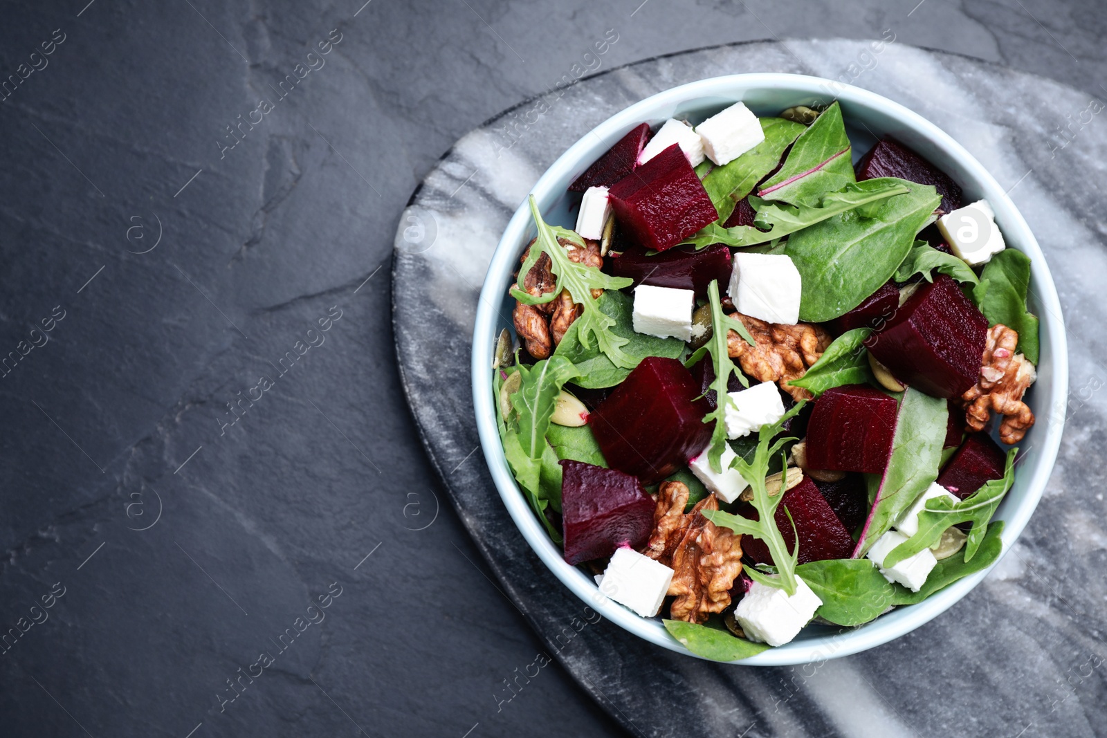 Photo of Delicious beet salad served on black table, top view. Space for text