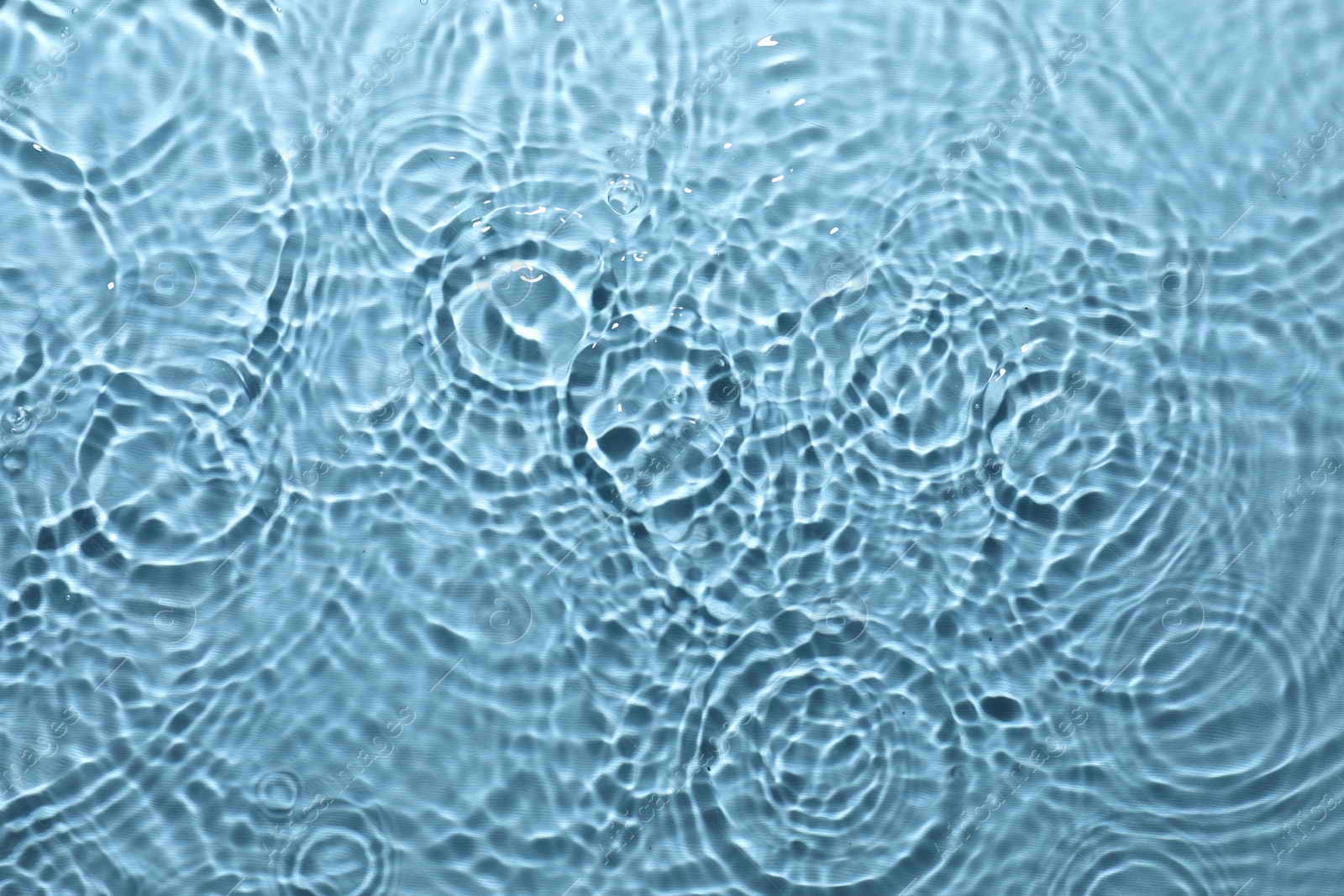 Photo of Rippled surface of clear water on light blue background, top view