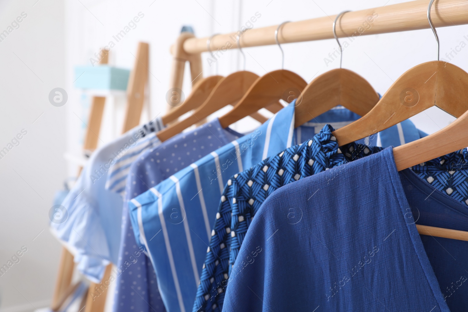 Photo of Rack with stylish hanging clothes in dressing room