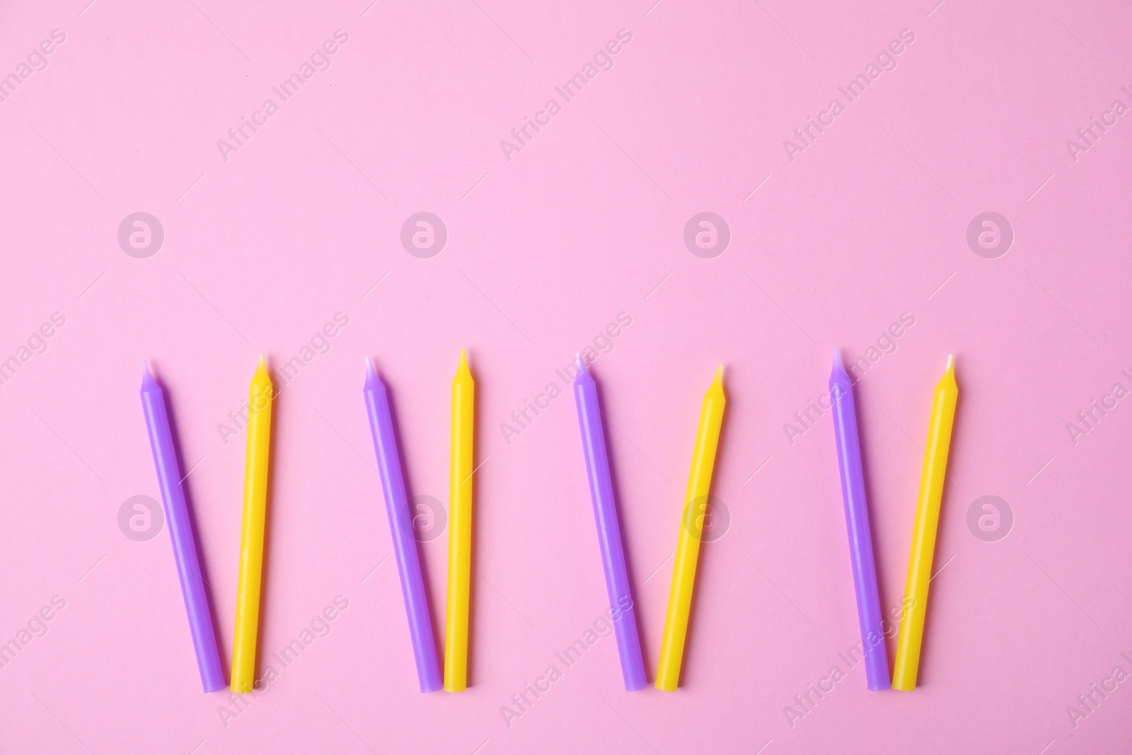 Photo of Bright birthday candles on pink background, flat lay