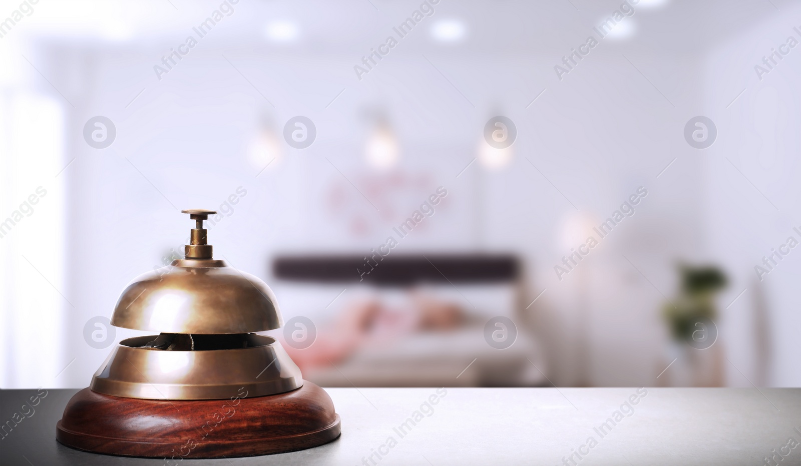 Image of Grey table with hotel service bell and blurred room on background. Space for text
