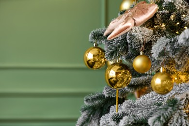 Photo of Beautiful decorated Christmas tree with baubles and lights near olive wall, closeup. Space for text