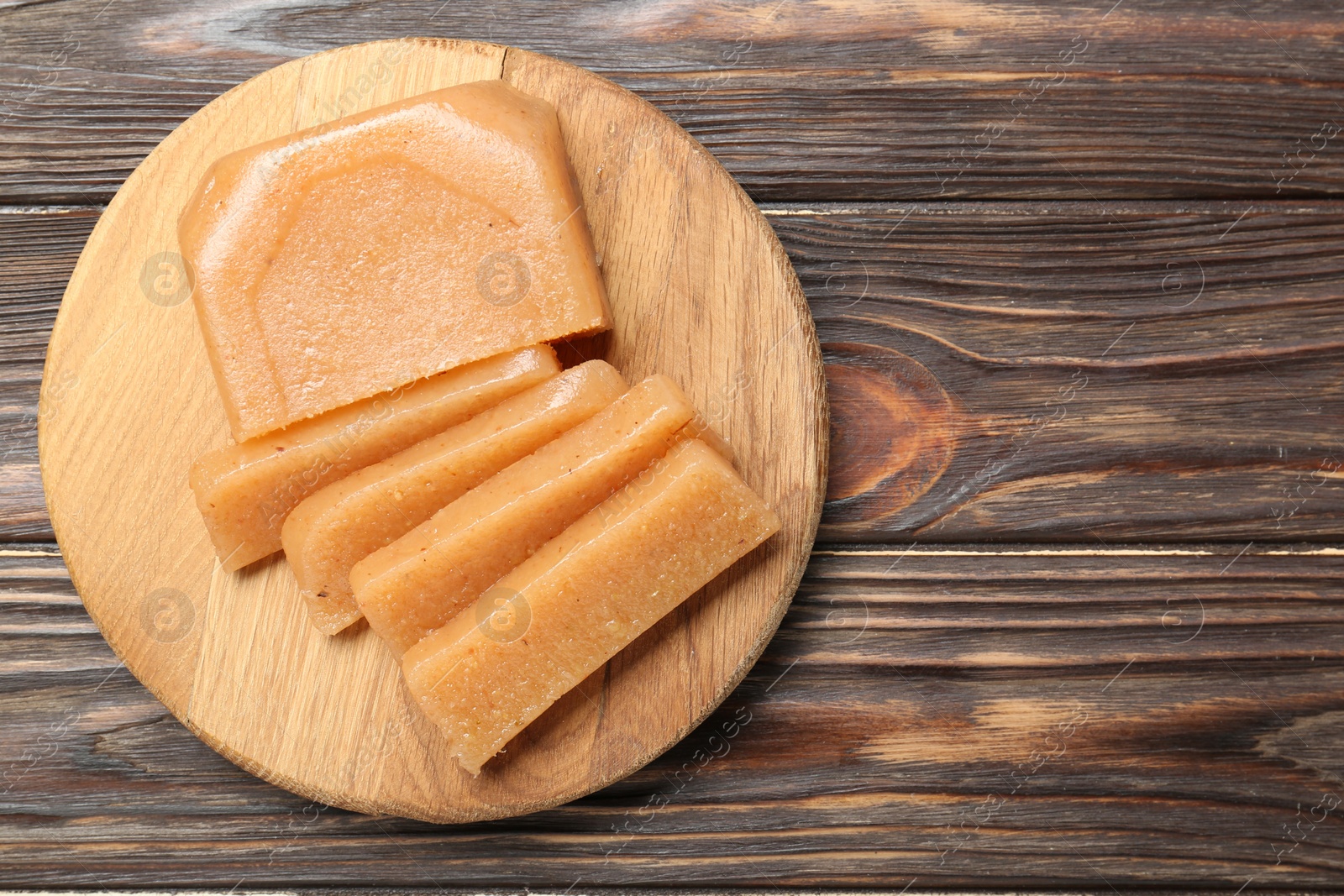 Photo of Tasty sweet quince paste on wooden table, top view. Space for text