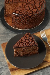 Photo of Delicious chocolate truffle cake and fork on grey textured table