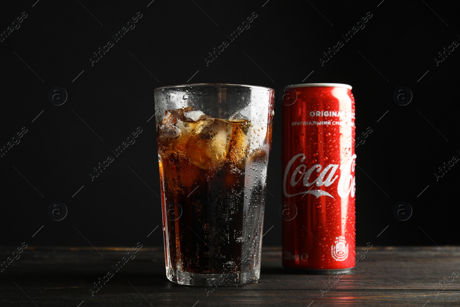 Photo of MYKOLAIV, UKRAINE - NOVEMBER 15, 2018: Glass and can with Coca Cola on table against black background