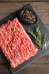 Photo of Raw ground meat, spices and rosemary on wooden table, top view