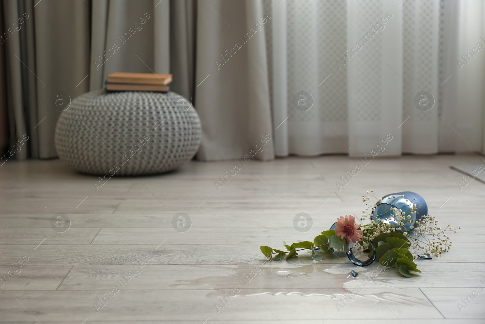 Photo of Broken blue glass vase and bouquet on floor in room. Space for text