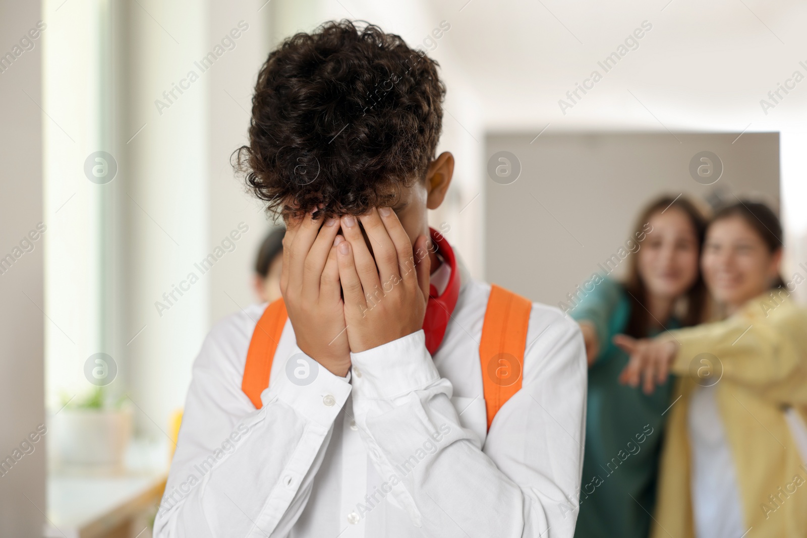 Photo of Teen problems. Students pointing at upset boy at school, selective focus